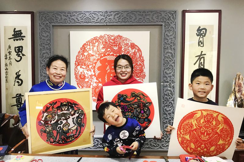 伏兆娥(左一)一家三代人展示剪纸作品。人民网 赵茉钰摄