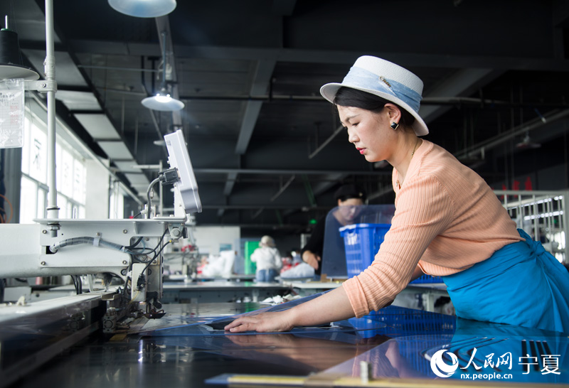 女工操作智能裁床裁剪布料。 人民网 张海峰摄