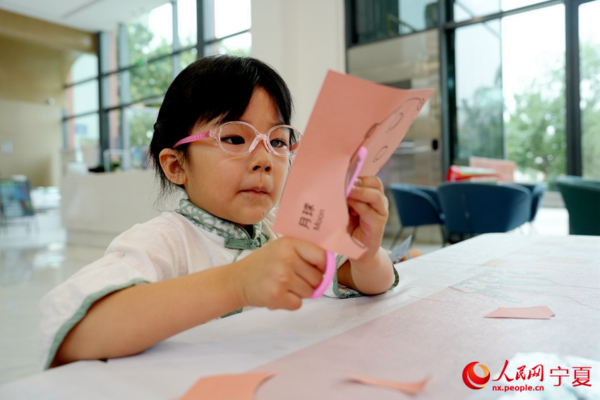 7月23日，宁夏银川市居安家园社区“暑托班”里，一名小朋友正在剪纸。人民网记者 阎梦婕摄