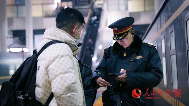 K1297次列车的乘务员正在车厢门口核验席位,迎接旅客乘车。人民网记者 梁宏鑫摄