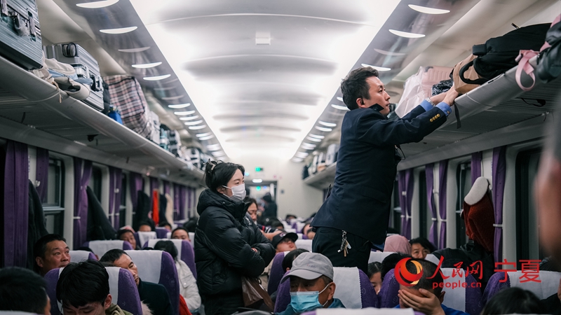 从银川开往上海方向的K359次列车乘务员正在帮助旅客摆放行李。人民网记者 梁宏鑫摄