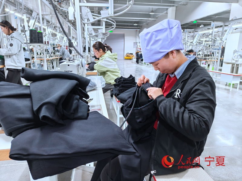 车间工作人员正在缝制裤子。人民网记者 李甜甜摄