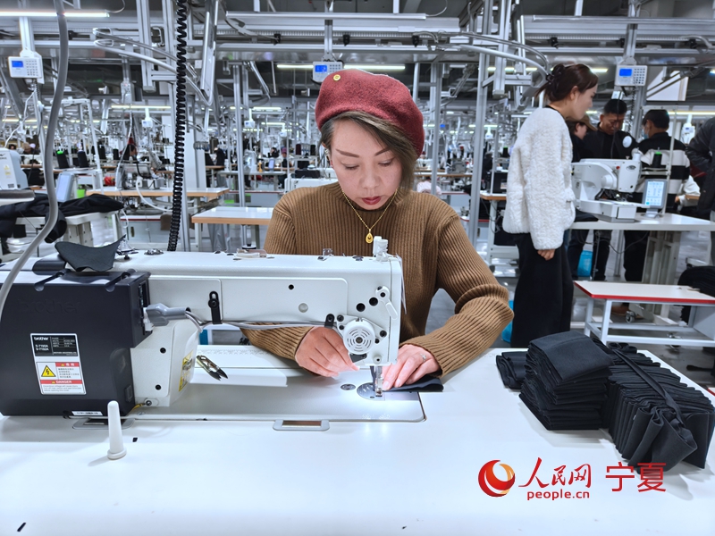 车间工作人员正在扎裤边。人民网记者 李甜甜摄